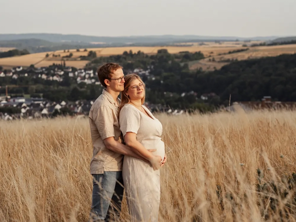 Paar im Kornfeld steht Arm in Arm in eine Richtung blickend