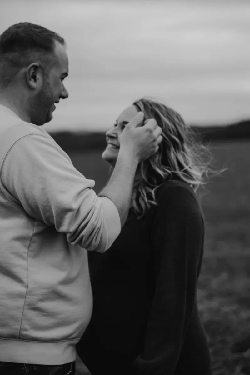 Mann streicht seiner schwangeren Frau sanft die Haare aus der Stirn