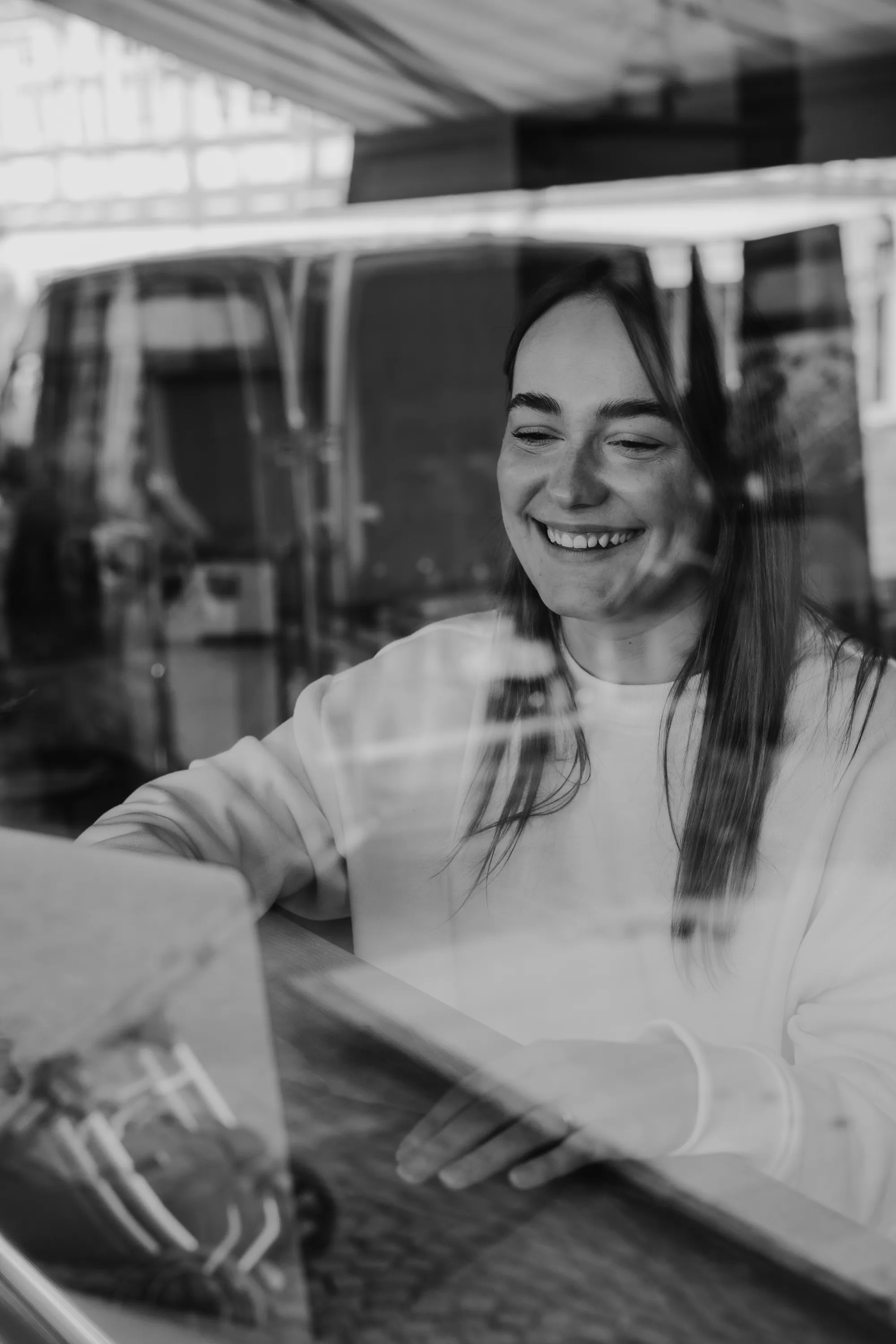 Caféinhaberin an Tisch von außen durch die Scheibe fotografiert