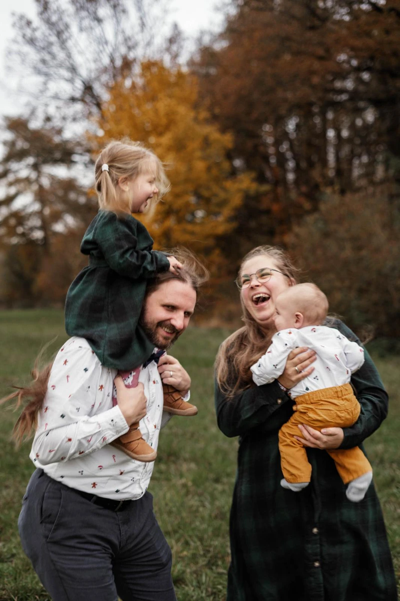 Familie mit Kindern auf Armen und Schulter lachen zusammen