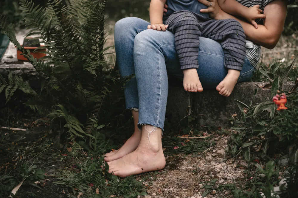 Mutter sitzt in Blumengarten mit Kind auf dem Schoß