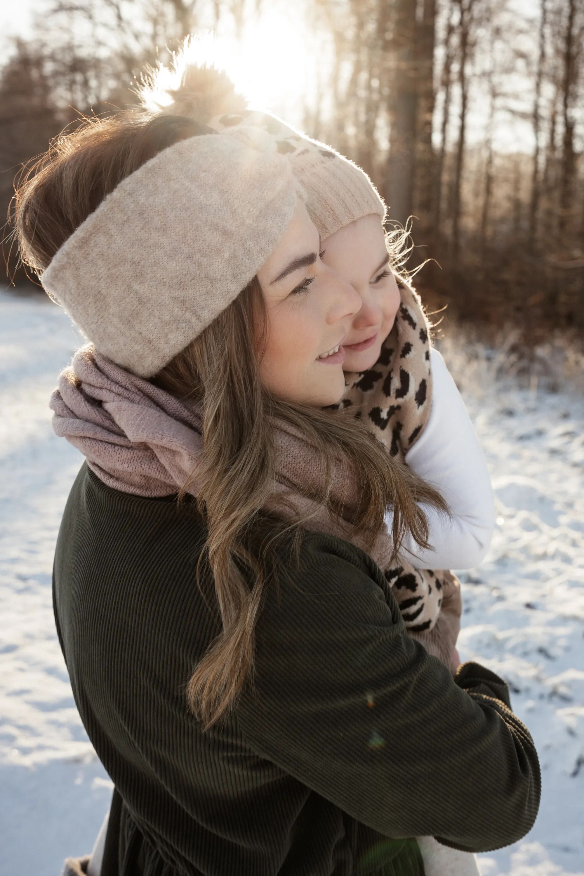 Mutter im Schnee mit Kind auf dem Arm in der Sonne