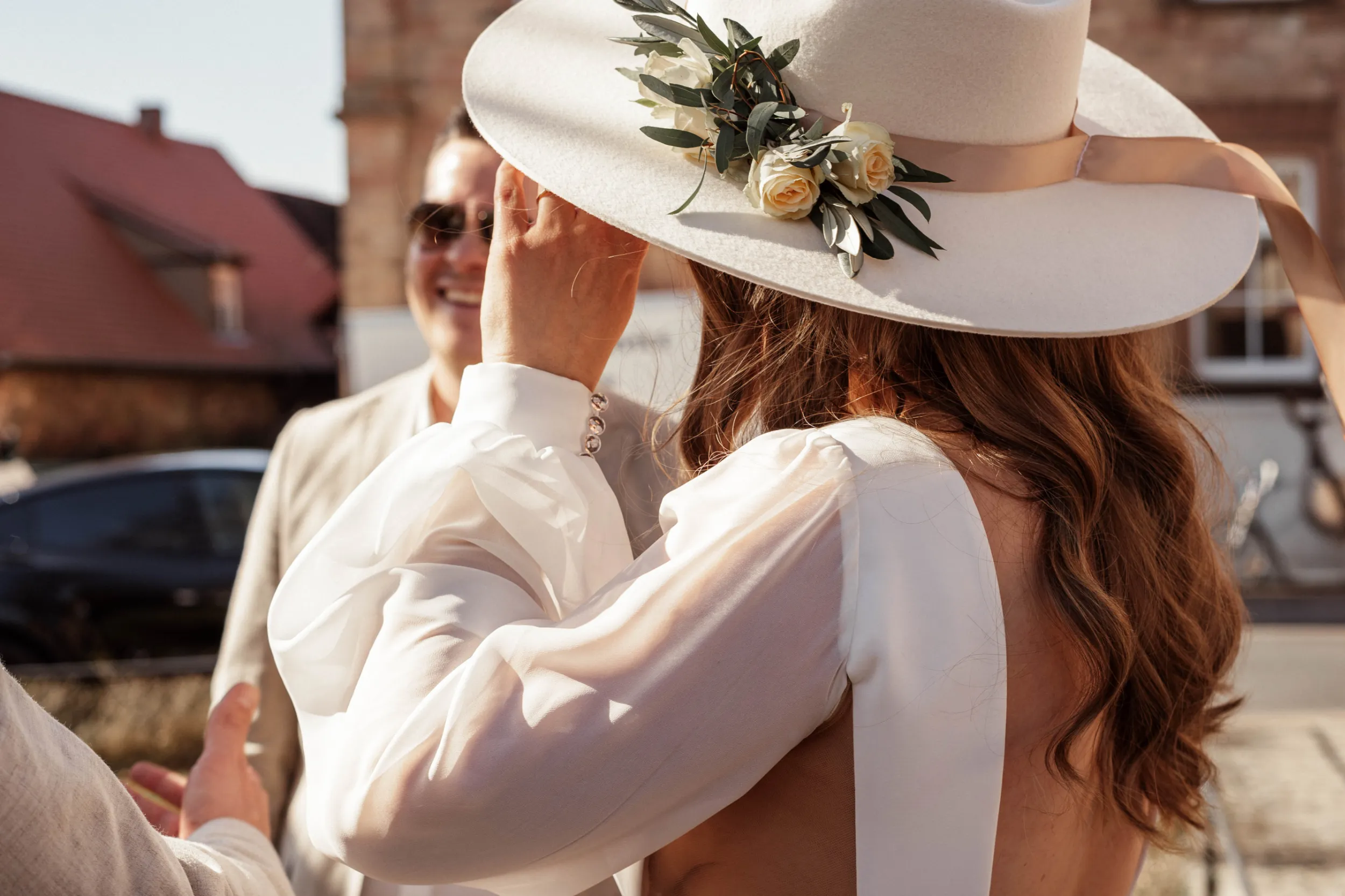 Braut mit Hut wird von Gästen beglückwünscht