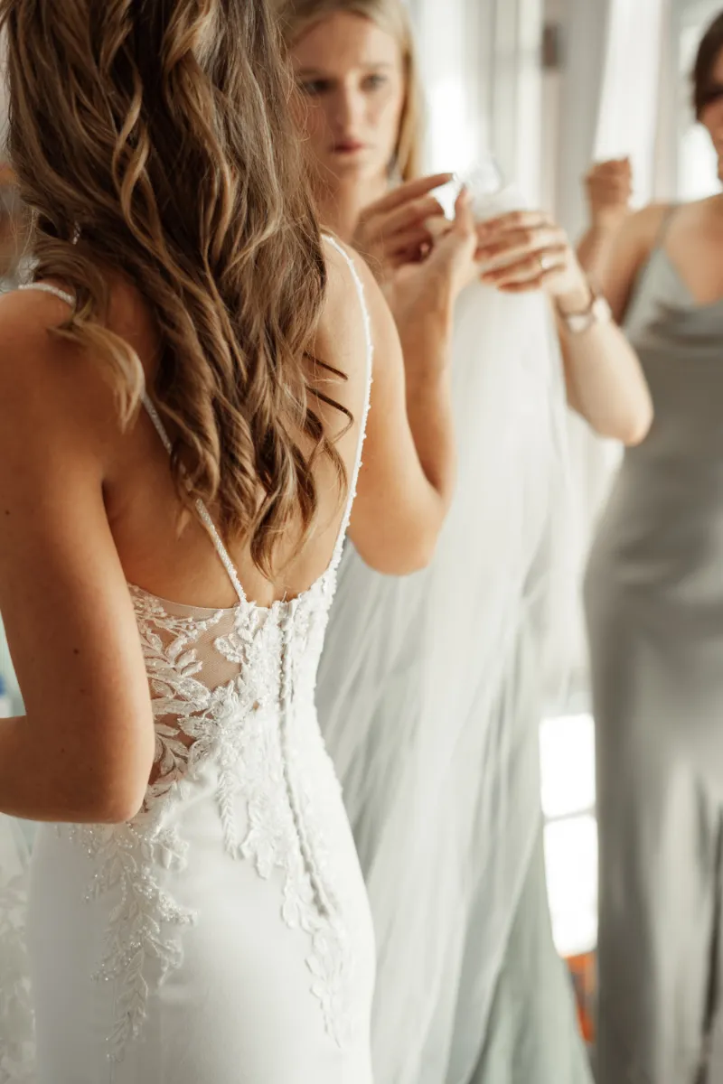 Freundin hilft Braut beim Schleier aufsetzen