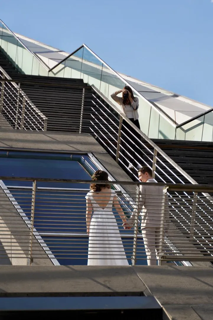 Jacky oben auf einer Treppe fotografiert Brautpaar unten