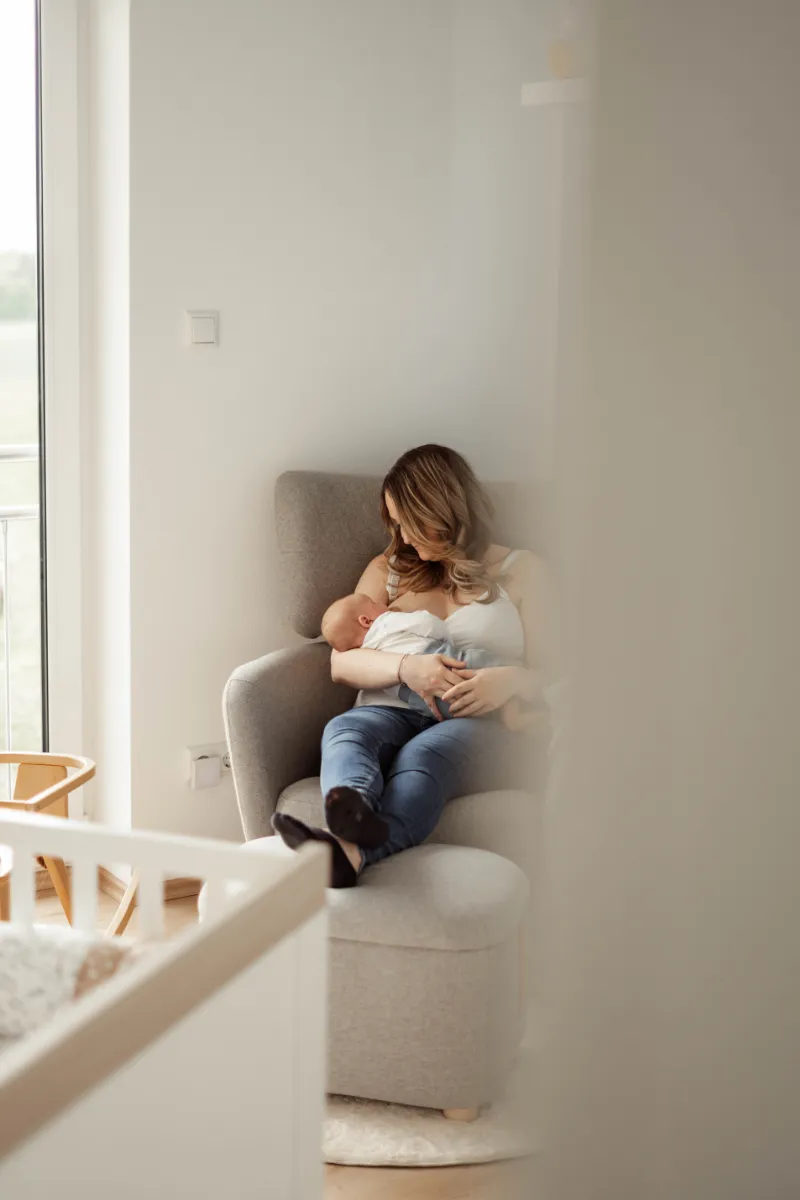 Blick durch Zimmertür Mama stillt Neugeborenes