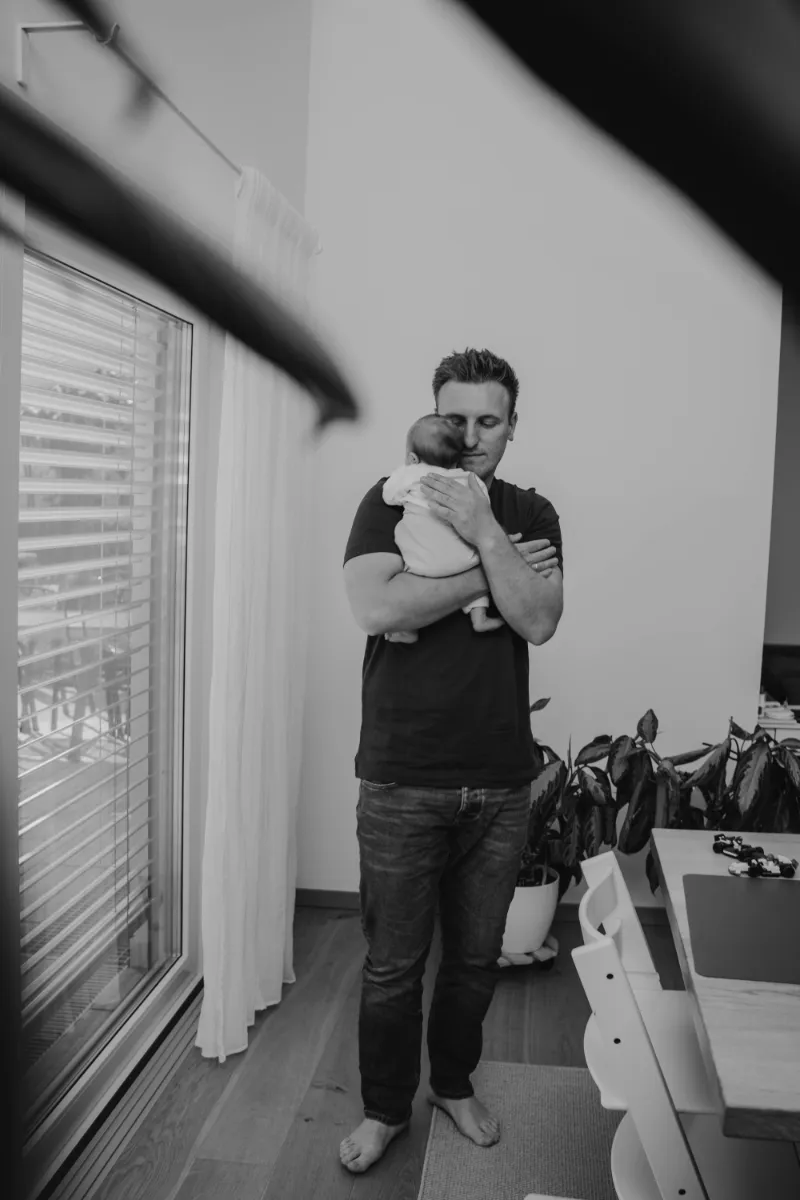 Papa trägt Neugeborenes durchs Zimmer