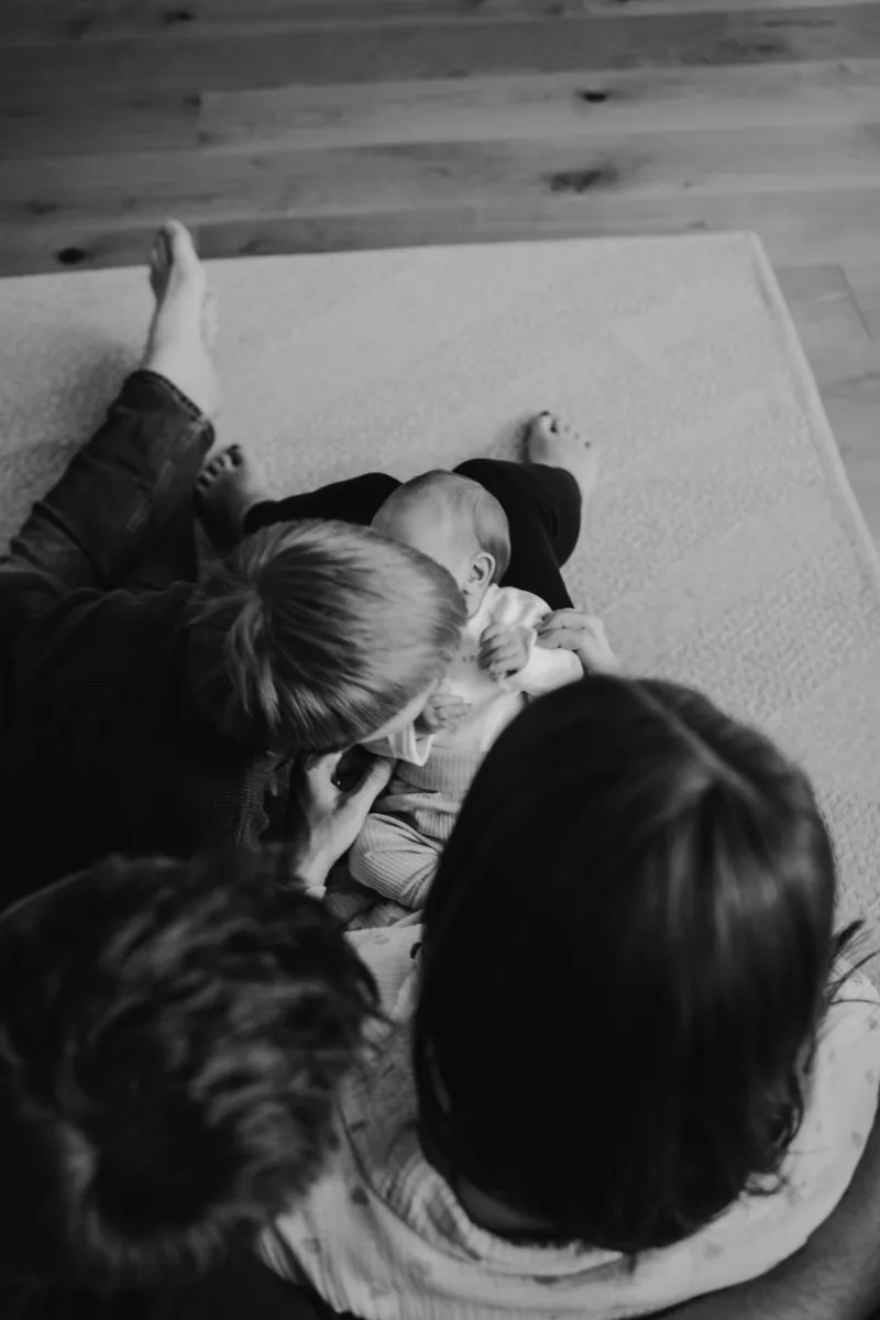 Perspektive von oben Familie versammelt sich ums Neugeborene bei Mama auf dem Schoß