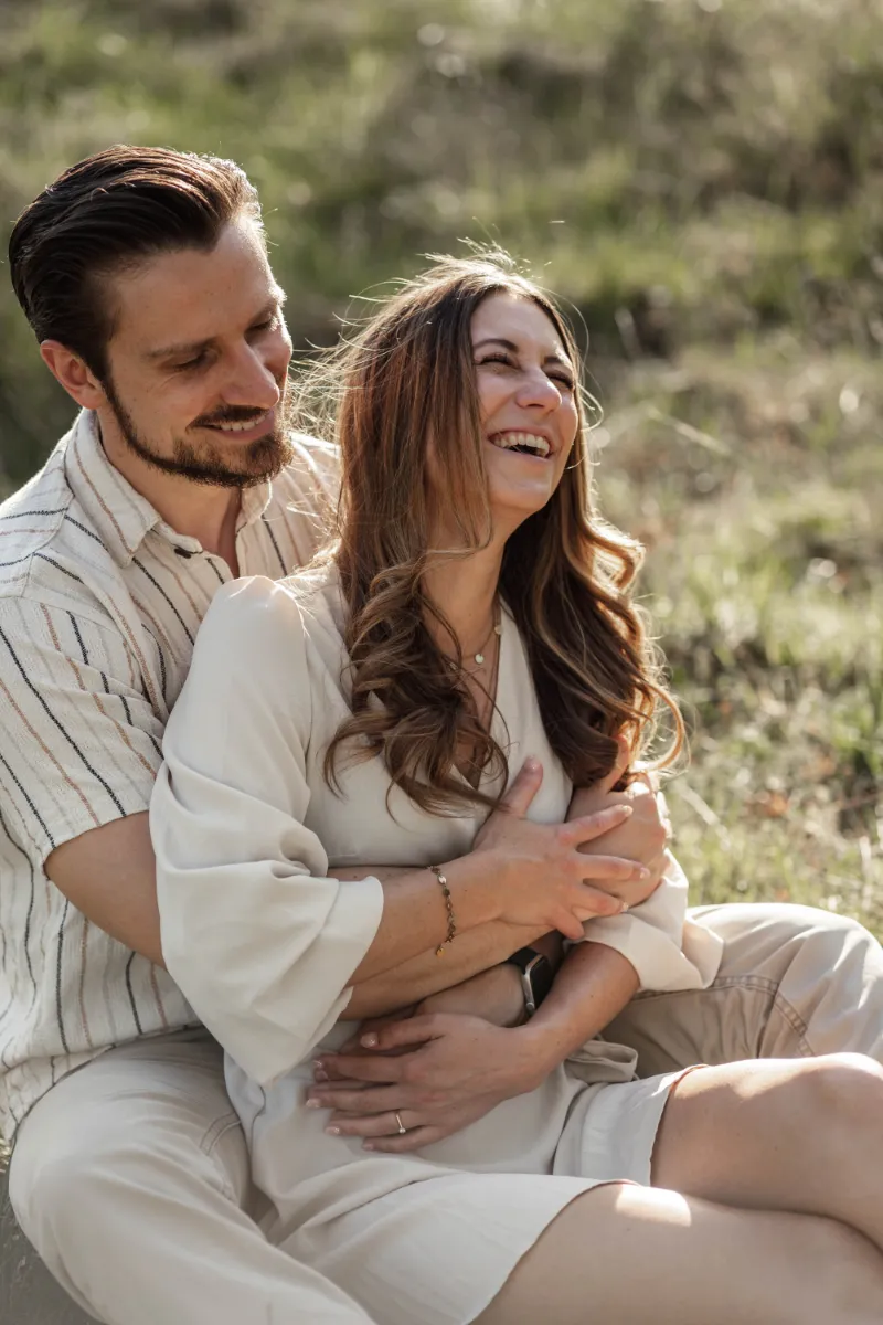 Lachendes Paar sitzt Arm in Arm auf der Wiese