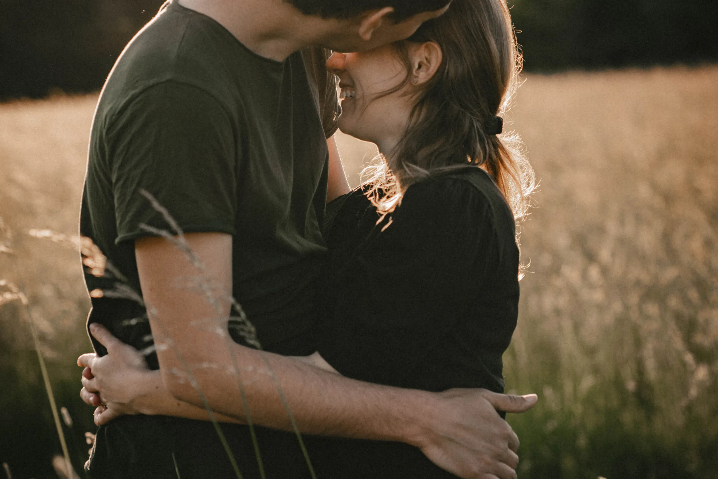 Nahaufnahme sich umarmendes Paar auf wilder Wiese zur Golden Hour
